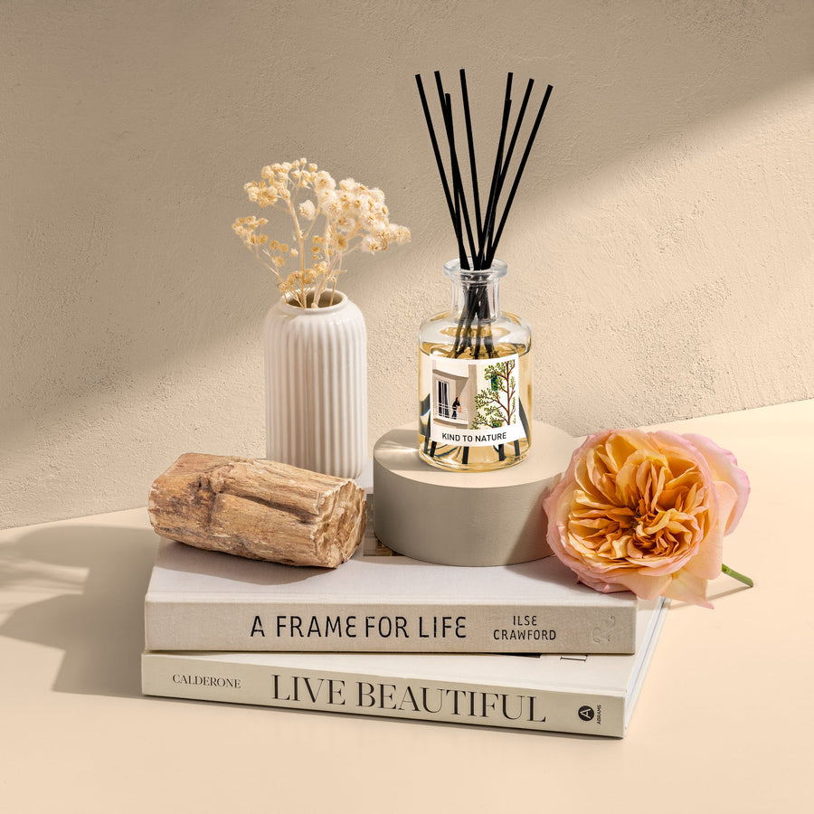 Elle Cadeaux Velvet Peony 6oz luxury reed diffuser styled with fresh peony bloom, driftwood and books in warm lifestyle setting
