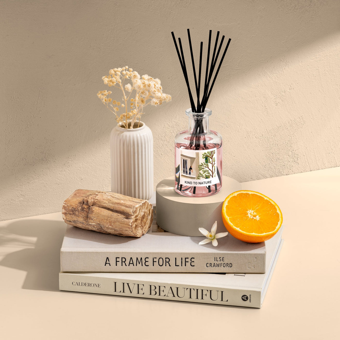 Elle Cadeaux Warm Orange Blossom reed diffuser styled with orange slice, dried flowers and books in warm lifestyle setting