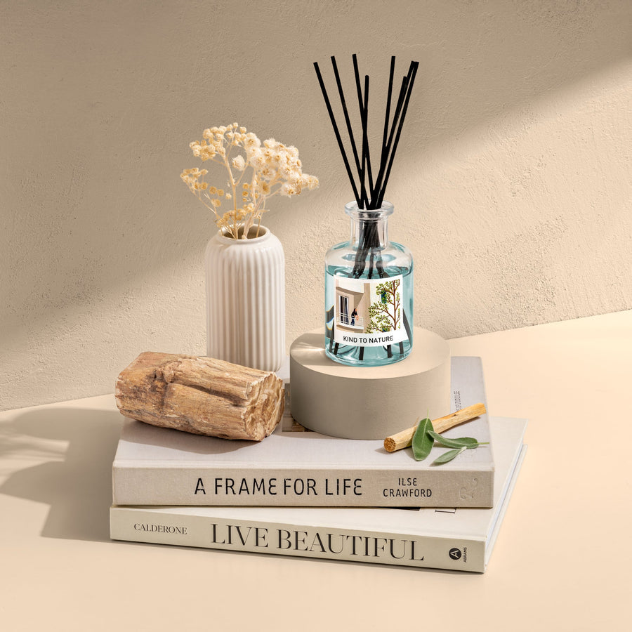 Elle Cadeaux Wood Sage & Sea Salt blue glass reed diffuser styled with driftwood, dried flowers and books in coastal lifestyle setting